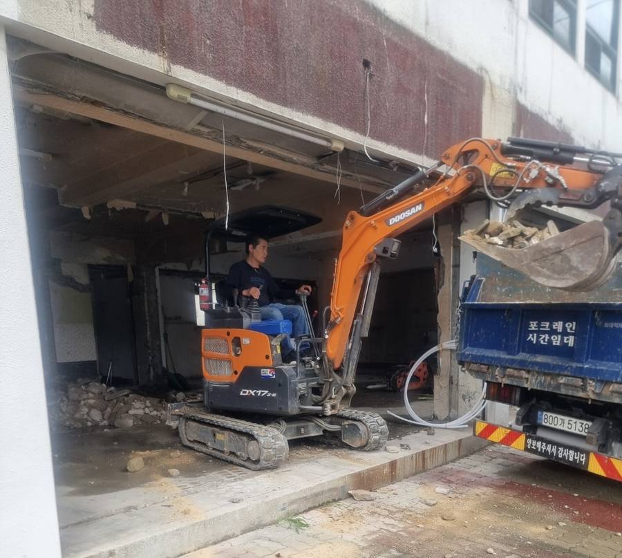 굴삭기로 철거 폐기물을 덤프트럭에 싣는 시공 현장